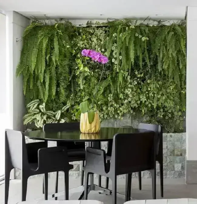 Um restaurante com teto preto e uma grande mesa com um monte de plantas  verdes.