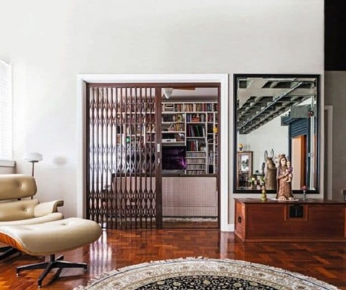 A porta pantográfica de ferro separa a sala de estar do restante dos ambientes