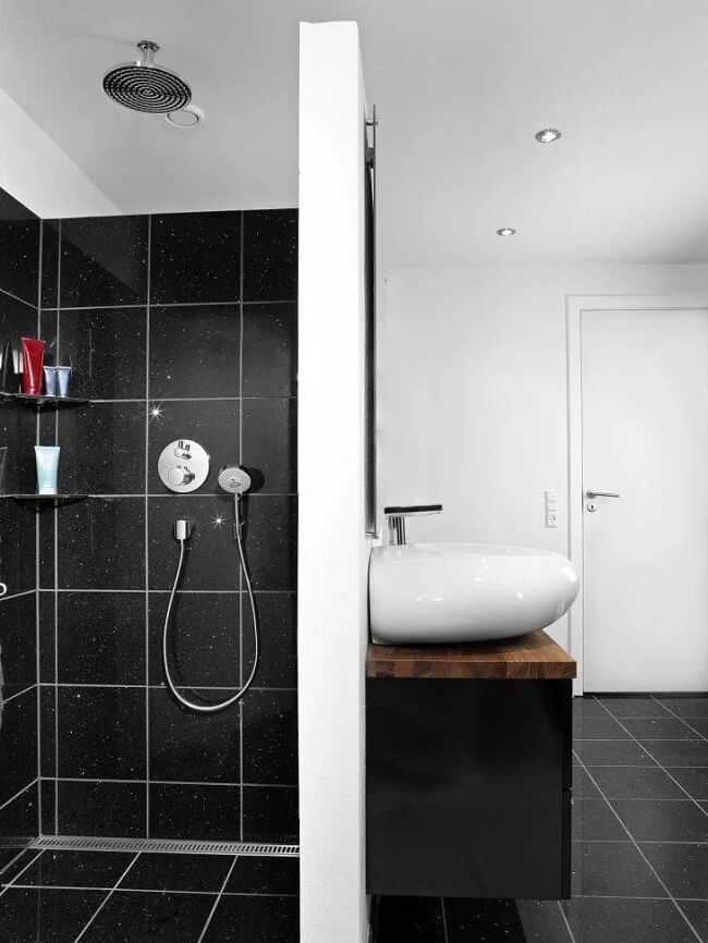 Banheiro de luxo com revestimento preto e chuveiro de teto