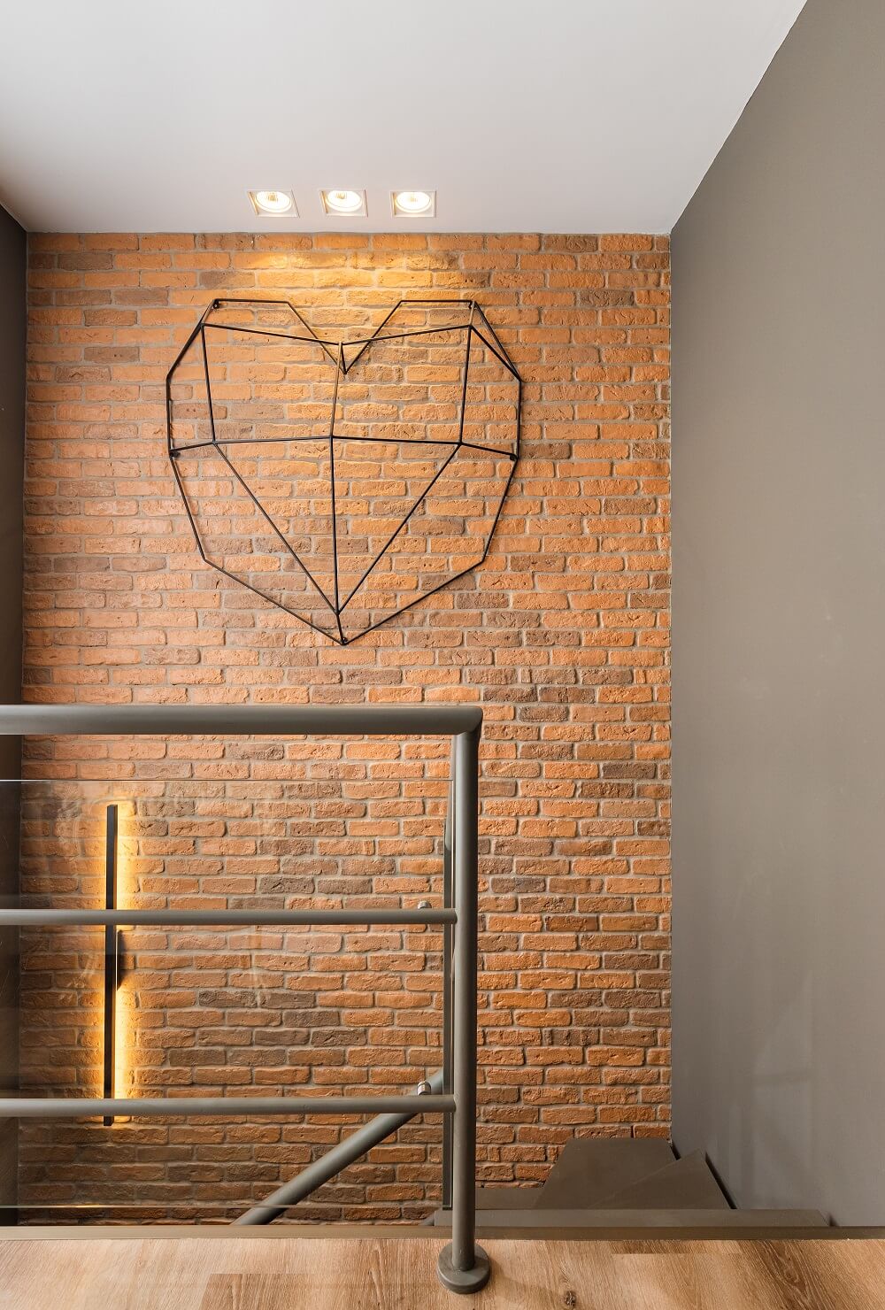 Parede de tijolinho aparente e coração em aramado se destaca na parede da escada. Foto: Fernando Crescenti 