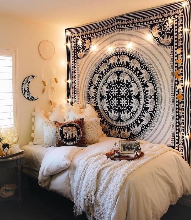 Tapeçaria de parede mandala e cordão de luzes decoram o quarto