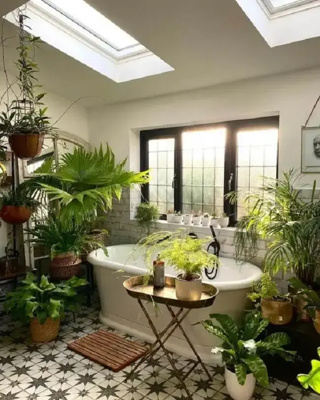 Banheiro com claraboia decorado com vários vasos de plantas