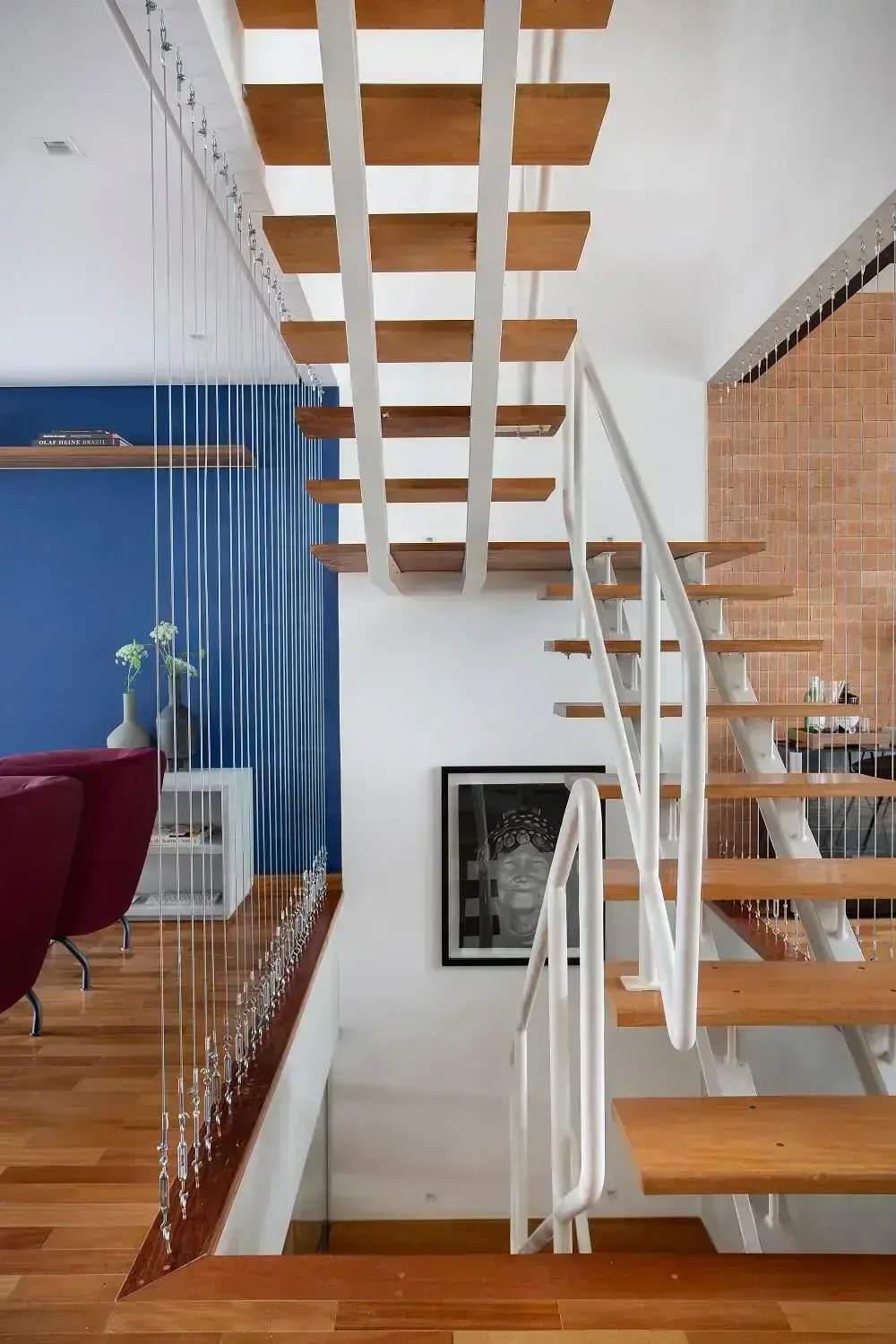 A escada com degraus de madeira dão acesso aos ambientes da casa