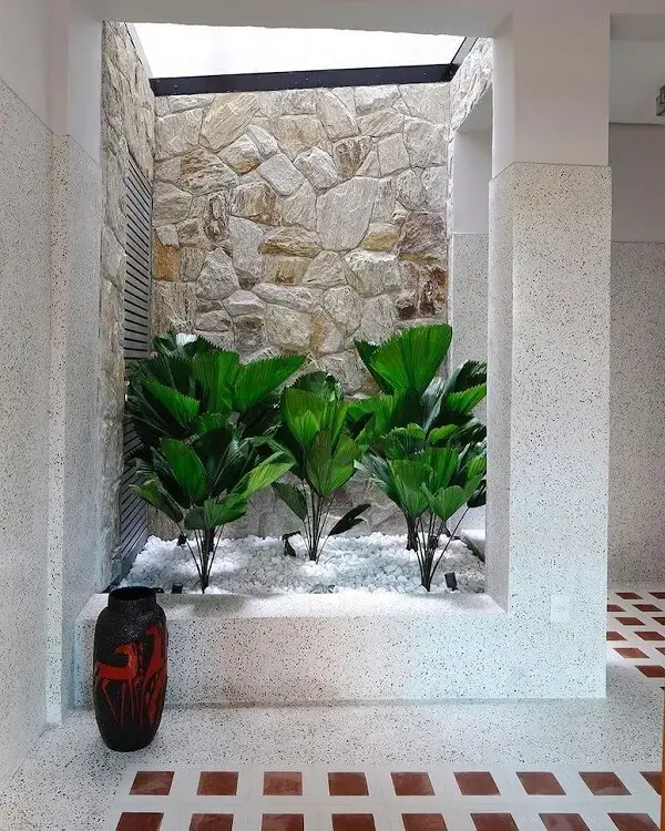 Ambiente acolhedora com vegetação e decoração com pedra branca para jardim