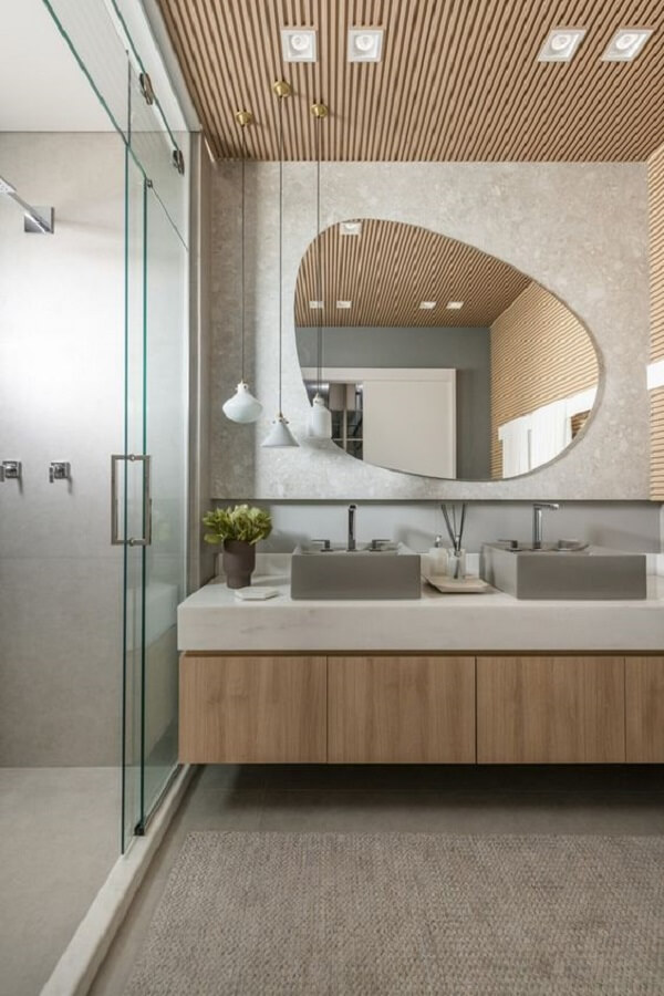 Banheiro com espelho em formato orgânico e box até o teto