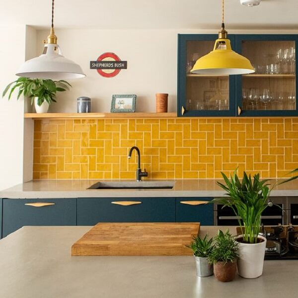 Cozinha planejada com bancada branca e revestimentos amarelos vibrantes