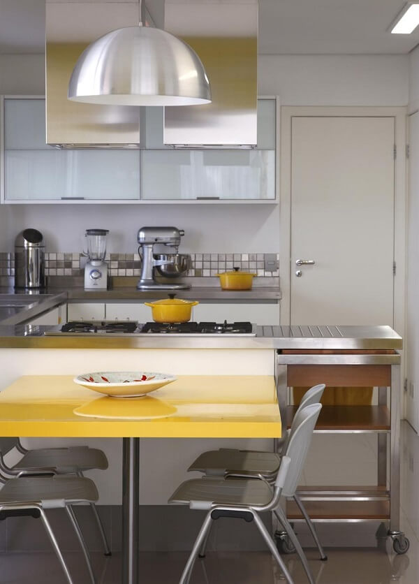Cozinha planejada com bancada em U e mesa amarela