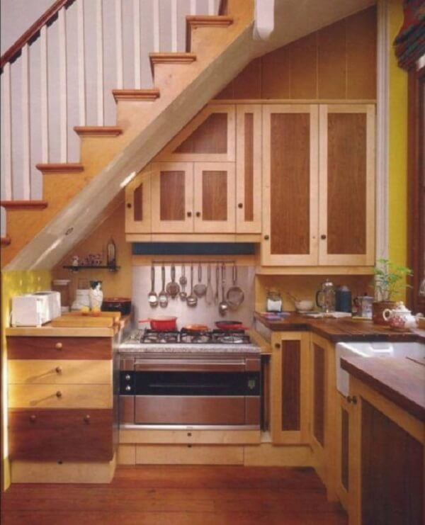 Mini cozinha com armários e gavetas projetada embaixo da escada