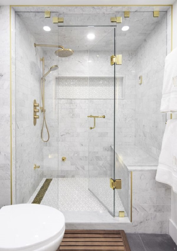 O ralo de banheiro linear e toques de dourado trazem elegância para o ambiente