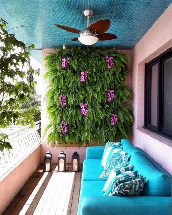 Sofá azul para área externa com parede de plantas e flores