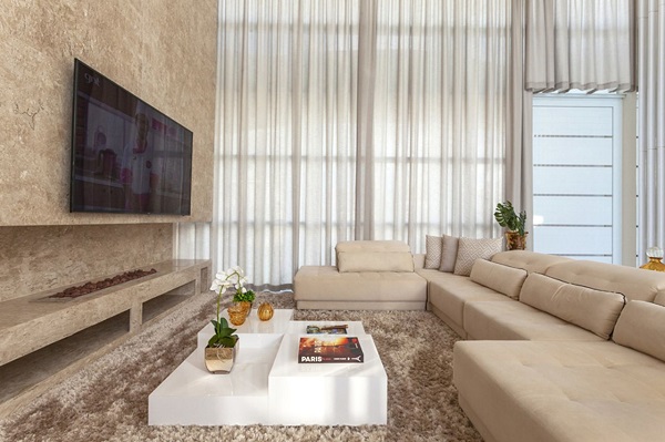 Sofá cor areia para sala de estar com janelas de vidro e painel de tv em mármore