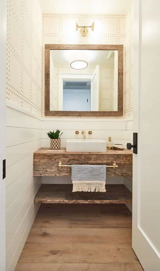 Banheiro pequeno decorado com espelho com moldura de madeira 