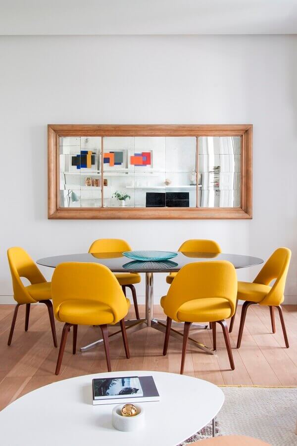 Decoração com cadeiras amarelas e espelho com moldura de madeira para sala de jantar Foto Elle Decor
