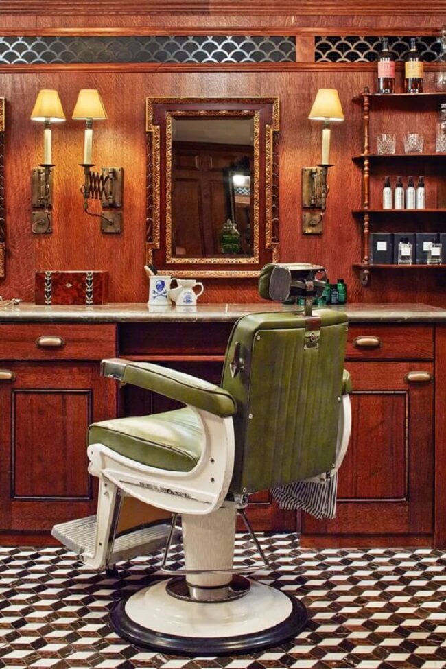 Uma cadeira de barbeiro em uma barbearia com um espelho na parede