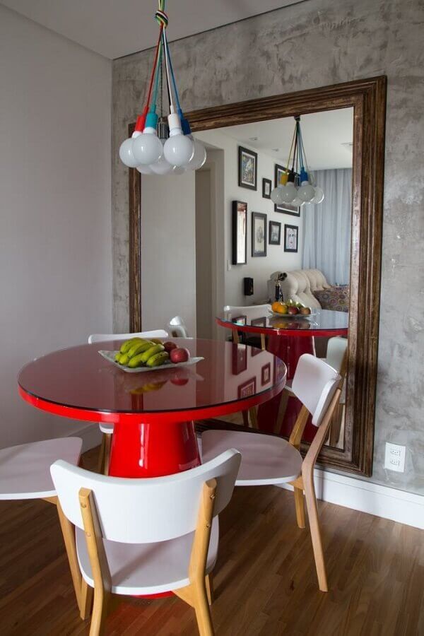 Espelho com moldura de madeira para sala de jantar decorada com mesa vermelha e parede de cimento queimado