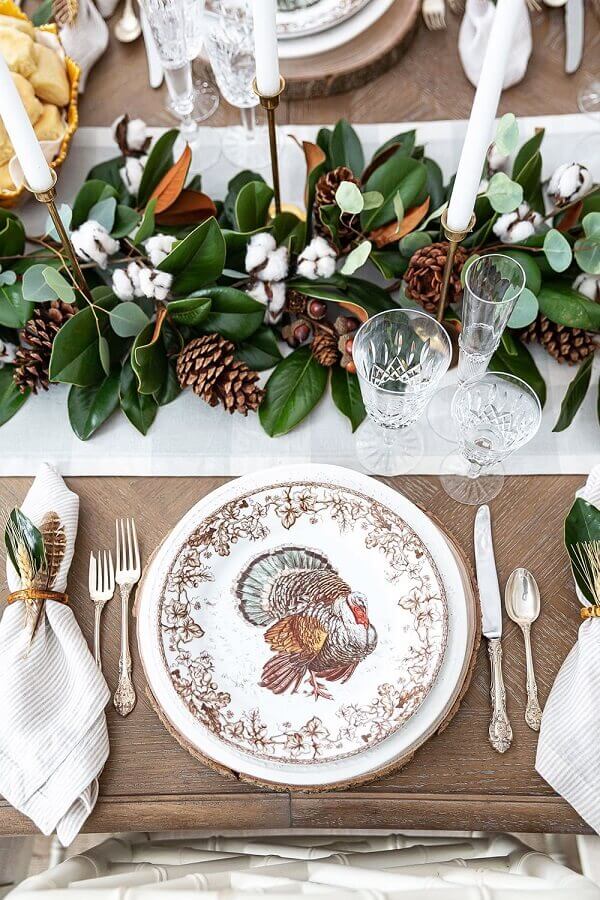 Arranjo rustico com folhagens e pinhas para decoração de mesa posta para ano novo Foto Pizzazzerie