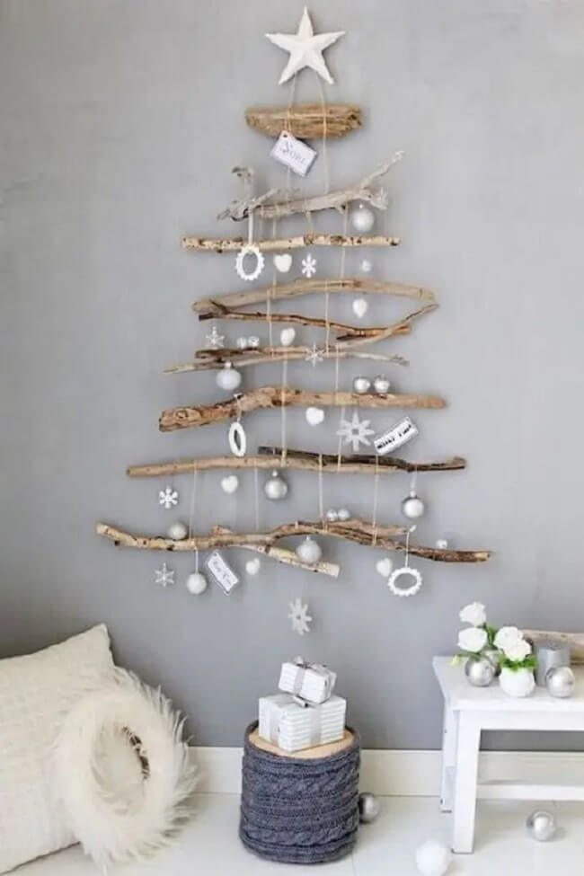 Árvore de natal de madeira na parede e enfeites em prata