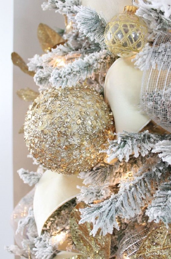 Árvore de natal nevada com enfeites dourados