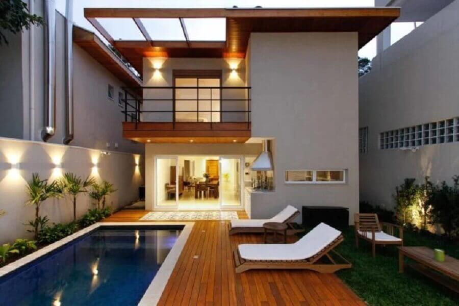 Casa com jardim e deck de madeira decorada com cadeira espreguiçadeira de piscina