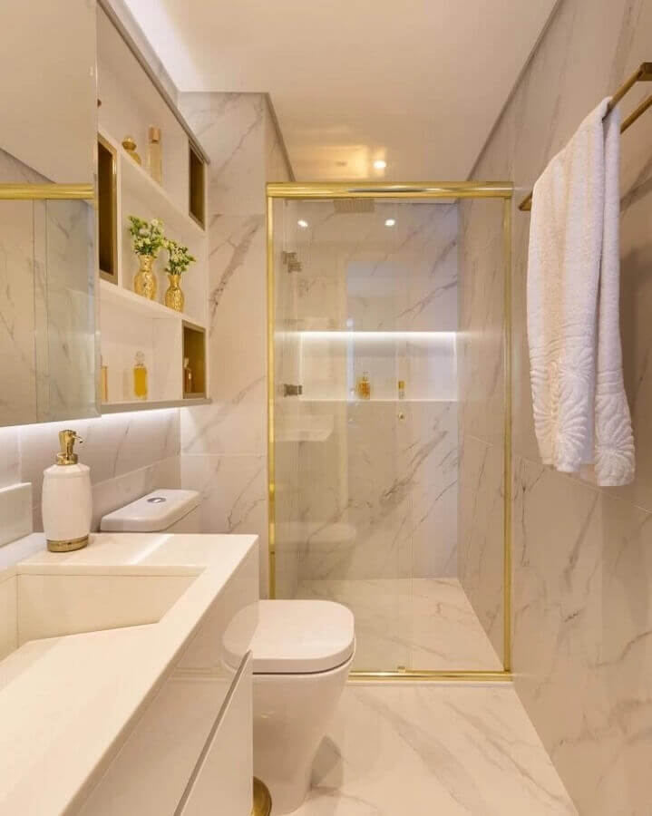 Cores claras para banheiro pequeno com nicho embutido decorado com detalhes em dourado 