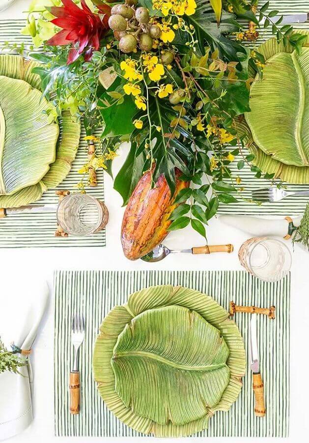 Mesa posta ano novo decorada com pratos em formato de folhas e jogo americano listrado