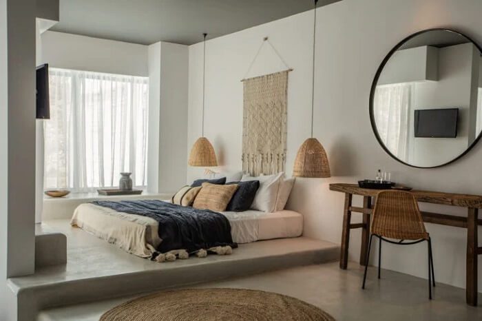 Tapete de sisal redonda, macramê e cama oriental decoram o quarto de casal